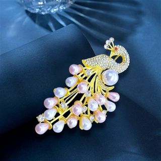 Đây là một chiếc trâm cài áo hình con công thanh lịch, thường được làm từ hợp kim mạ vàng, đính kèm ngọc trai (có thể là ngọc trai nuôi cấy hoặc ngọc trai nước ngọt) và các viên đá pha lê hoặc zircon lấp lánh. Kích thước 7cm